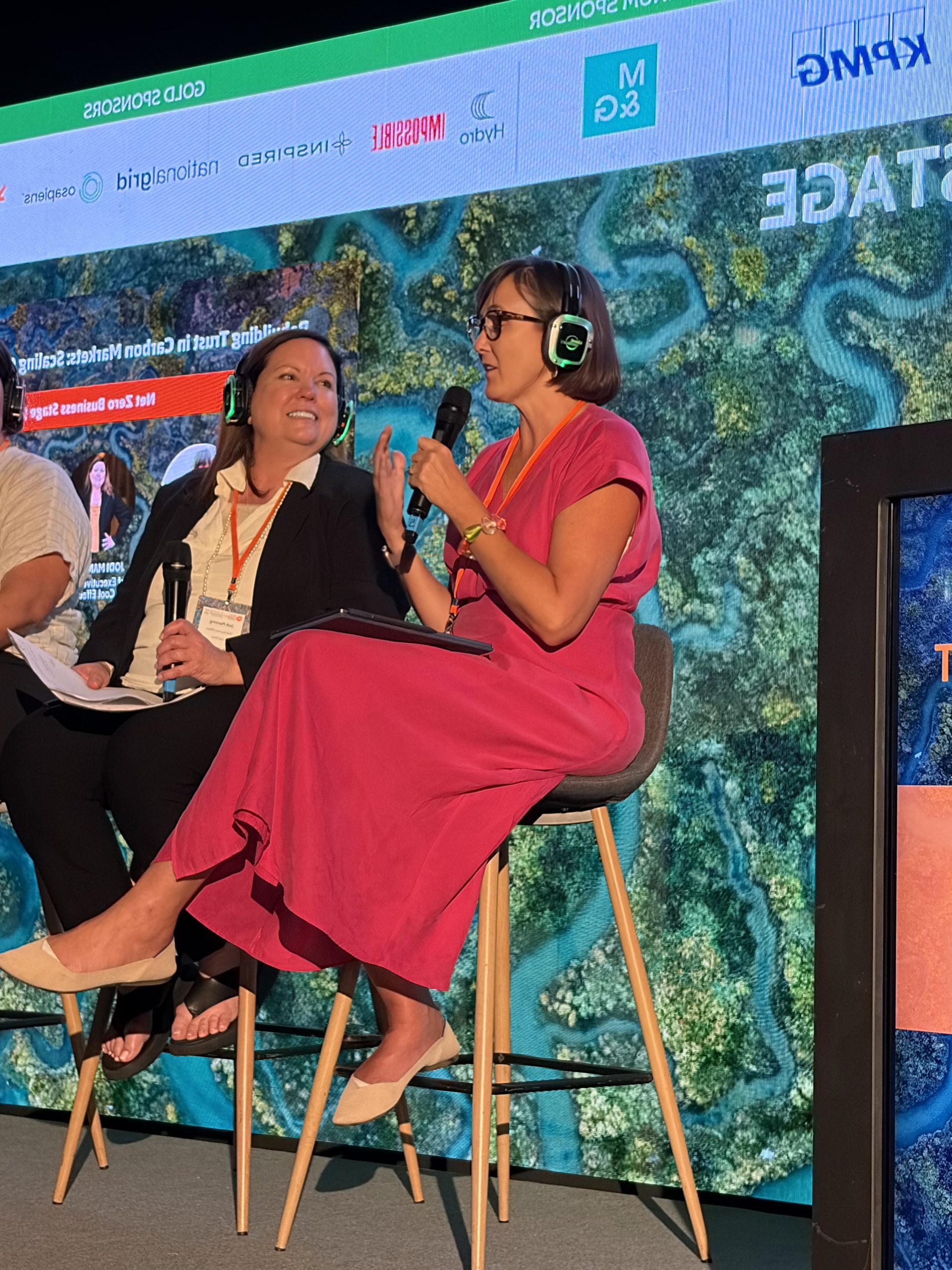 Jen Stebbing speaking into a microphone on the Net Zero Business Stage at Reset Connect London, with a panellist beside her