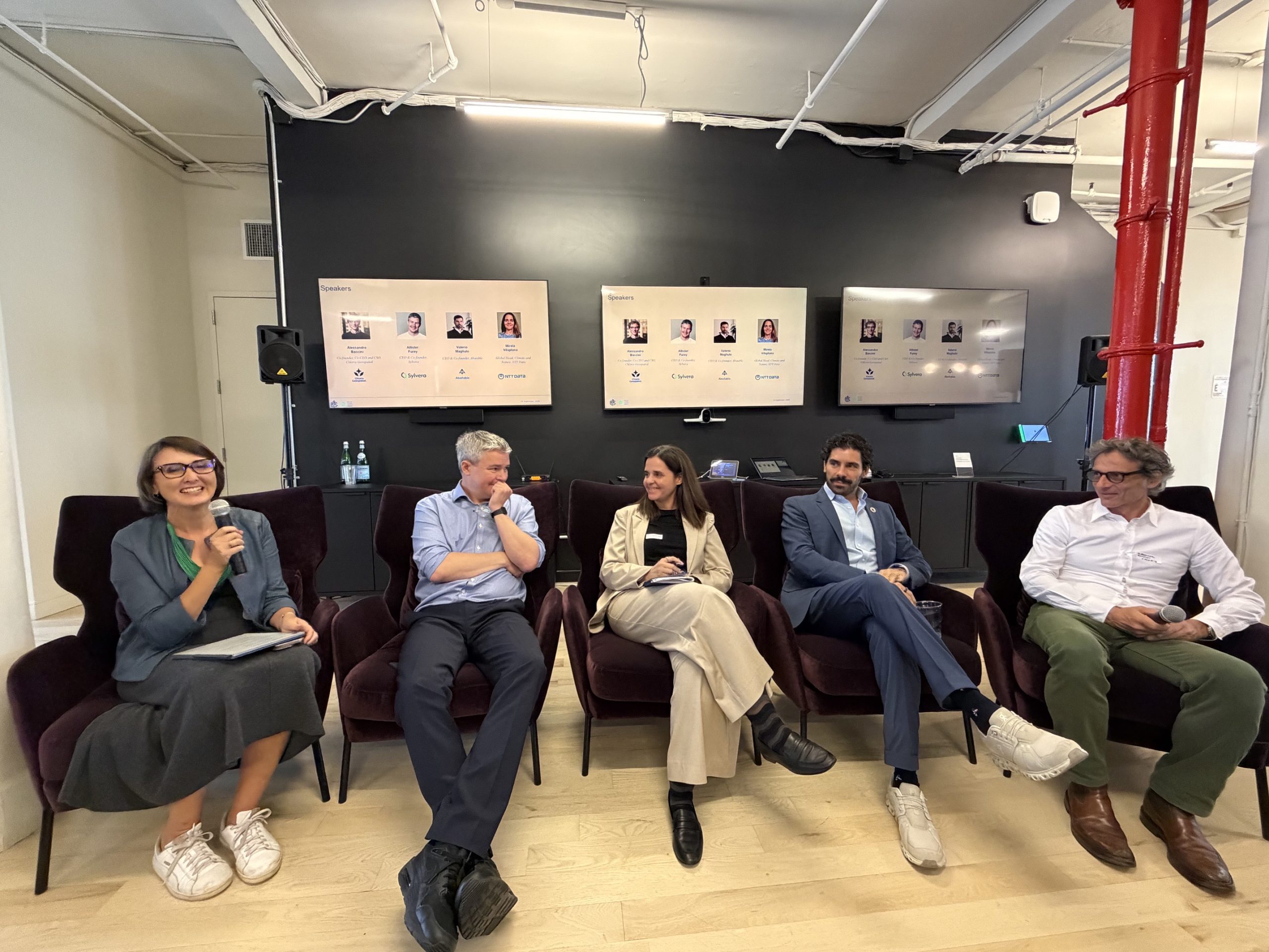 A five-person panel seated in armchairs at Climate Week NYC, the moderator on the left holding a microphone